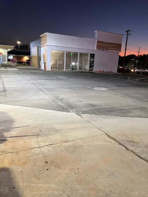 A parking lot with a building in the background at night.