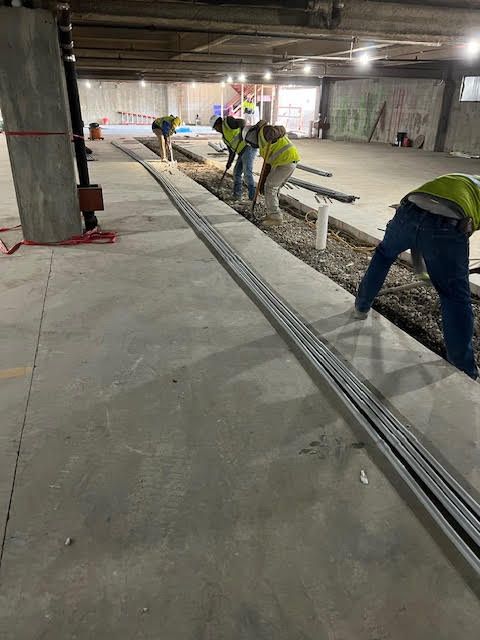 A group of construction workers are working on a concrete floor.