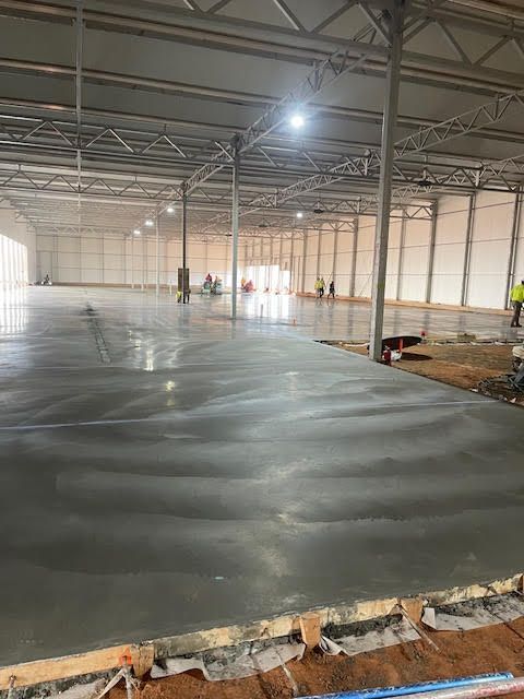 A large warehouse with a concrete floor under construction.