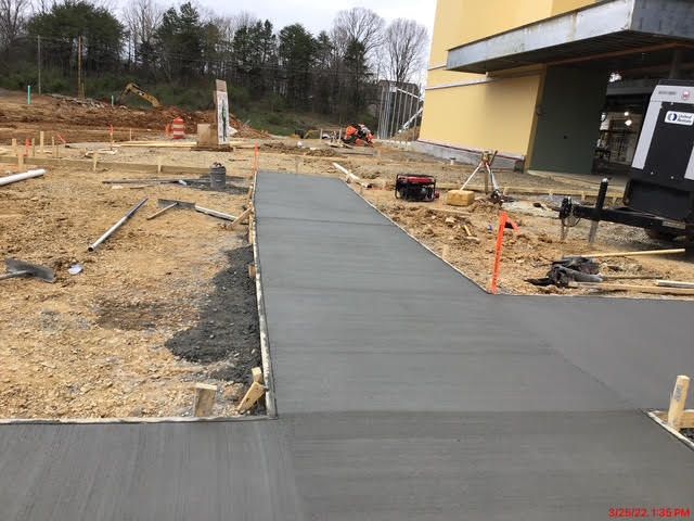 A concrete walkway is being built in front of a building.