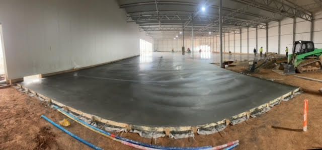 A large warehouse under construction with a concrete floor.