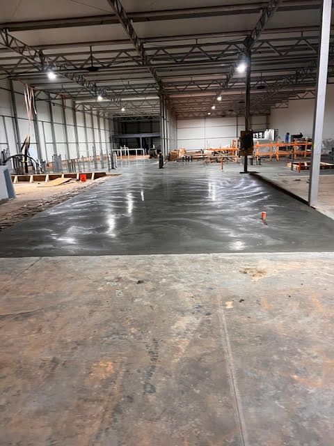 A large warehouse with a concrete floor under construction.