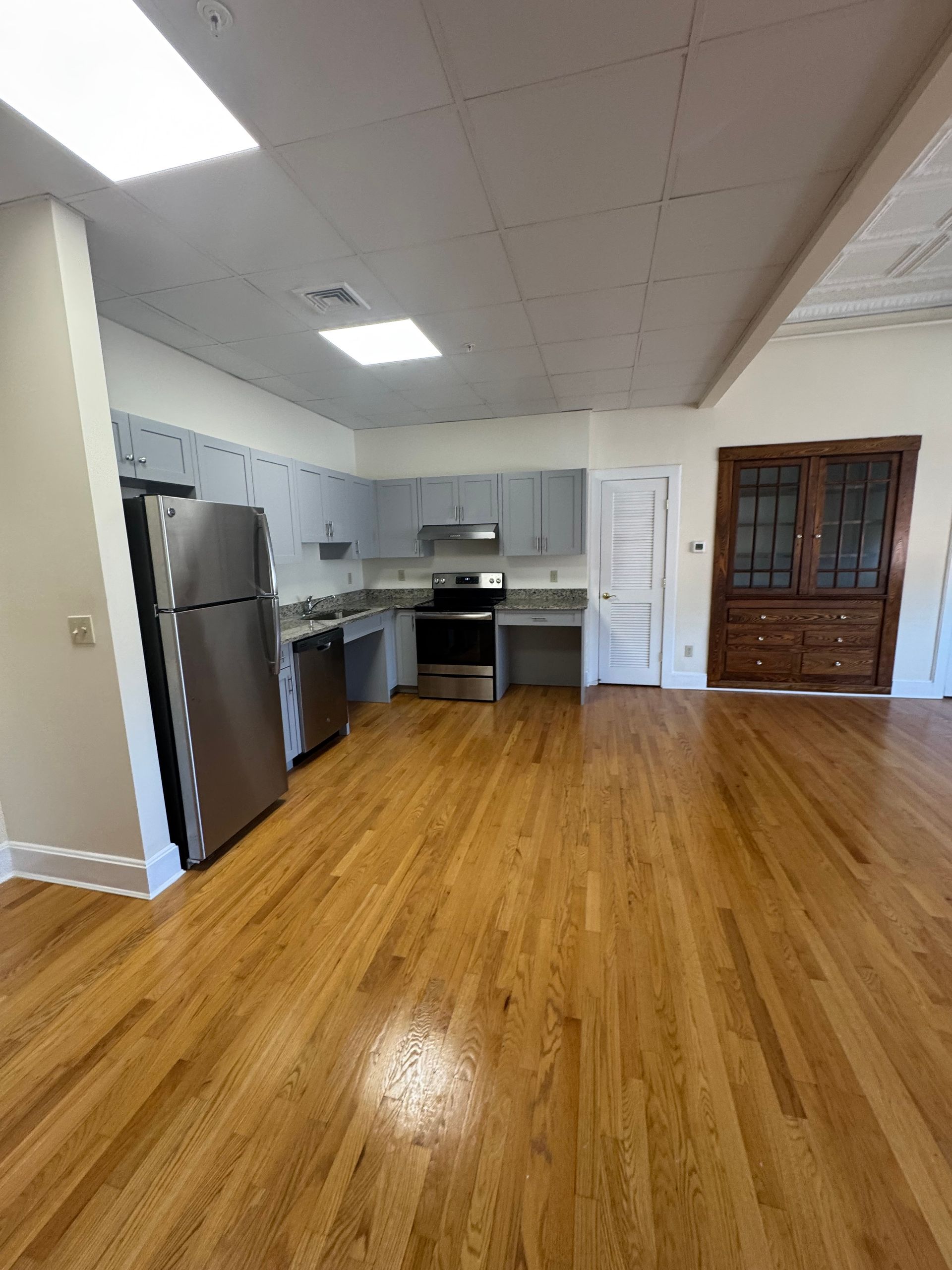 Spacious kitchen with stainless steel appliances, light blue cabinets, and hardwood floors. A large antique cabinet is in the corner.