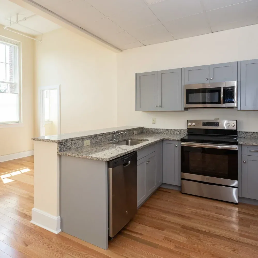 Modern kitchen with grey cabinets, stainless steel appliances, and granite countertops.