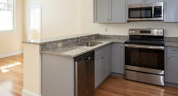 Gray kitchen with stainless steel appliances, granite countertops, and hardwood floors.