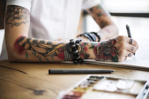 Ragazzo con braccio tatuato che scrive