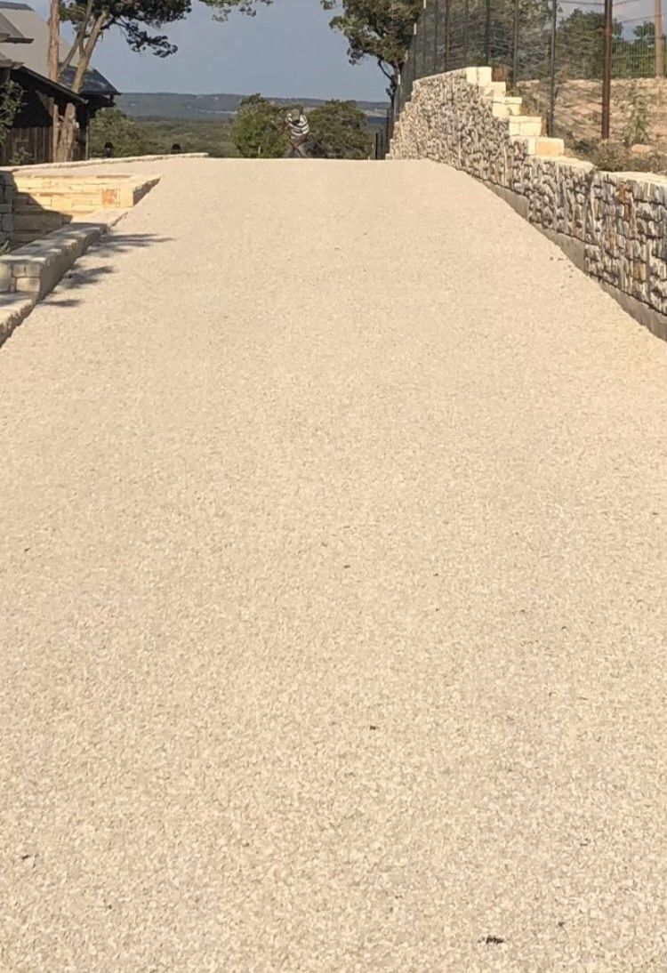 A gravel road with a stone wall on the side of it.