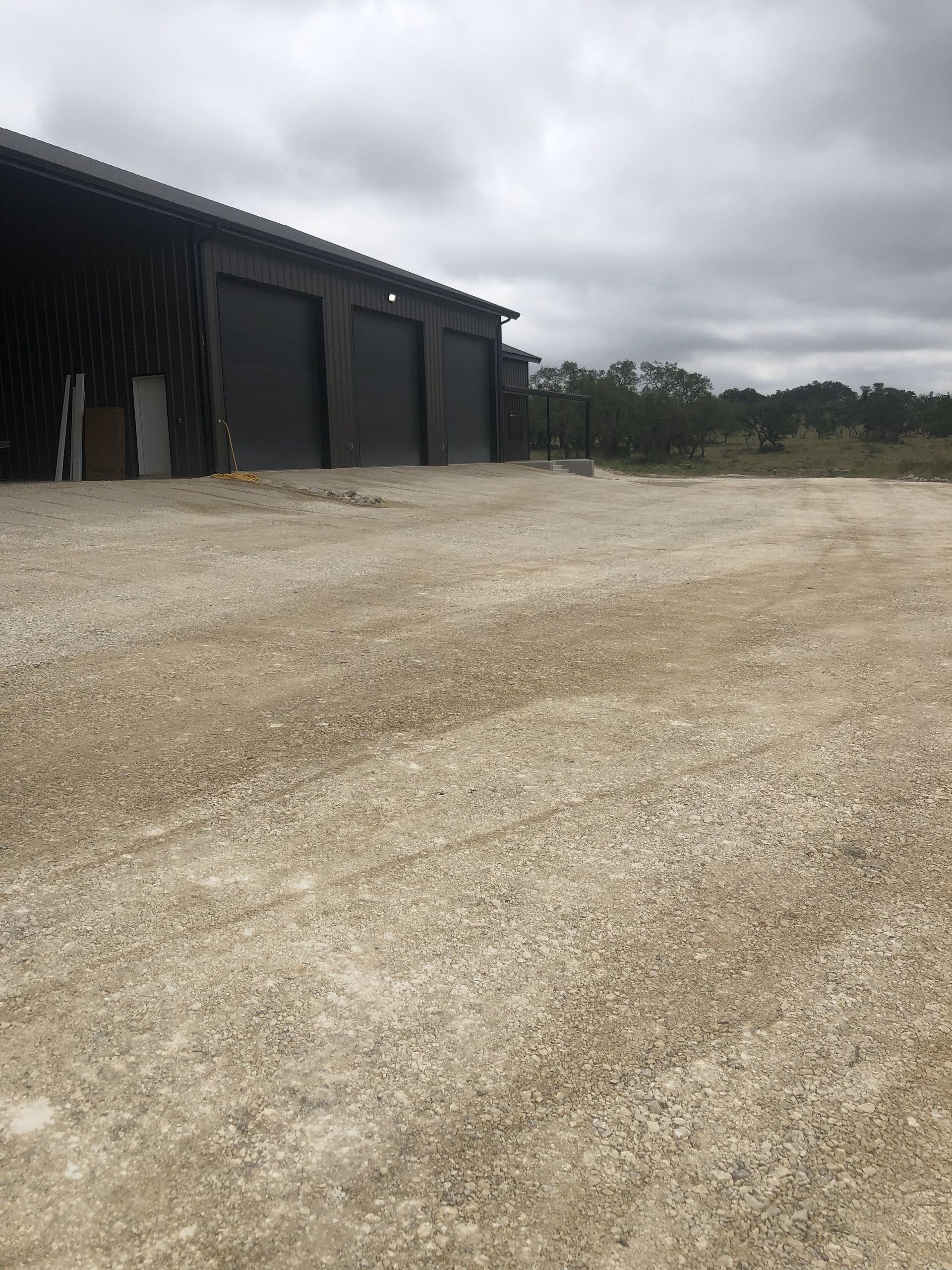 A large building with a lot of garage doors is sitting in the middle of a dirt field.