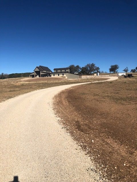 A dirt road leads to a house in the distance