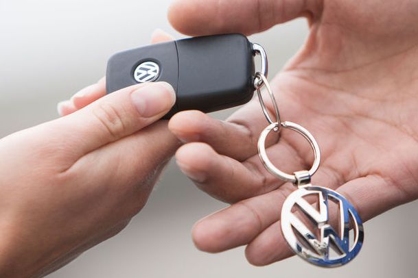 A person is handing a car key to another person