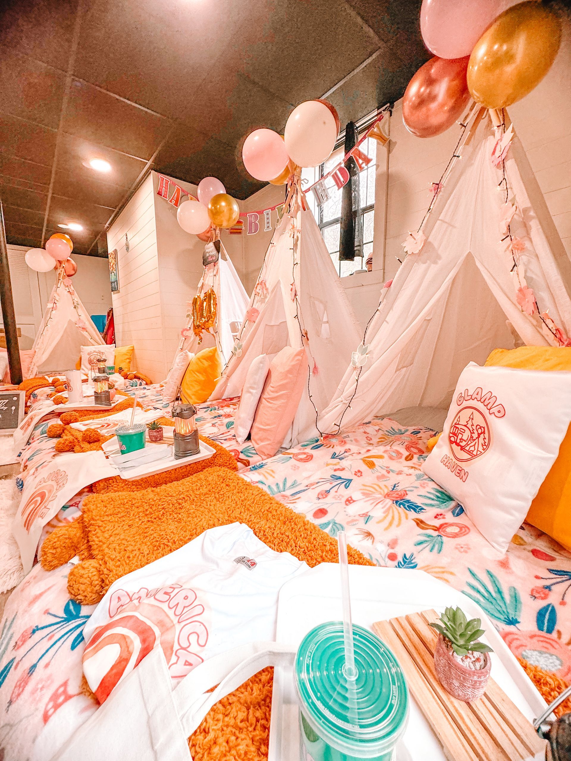 A group of people are laying in tents in a room with balloons.