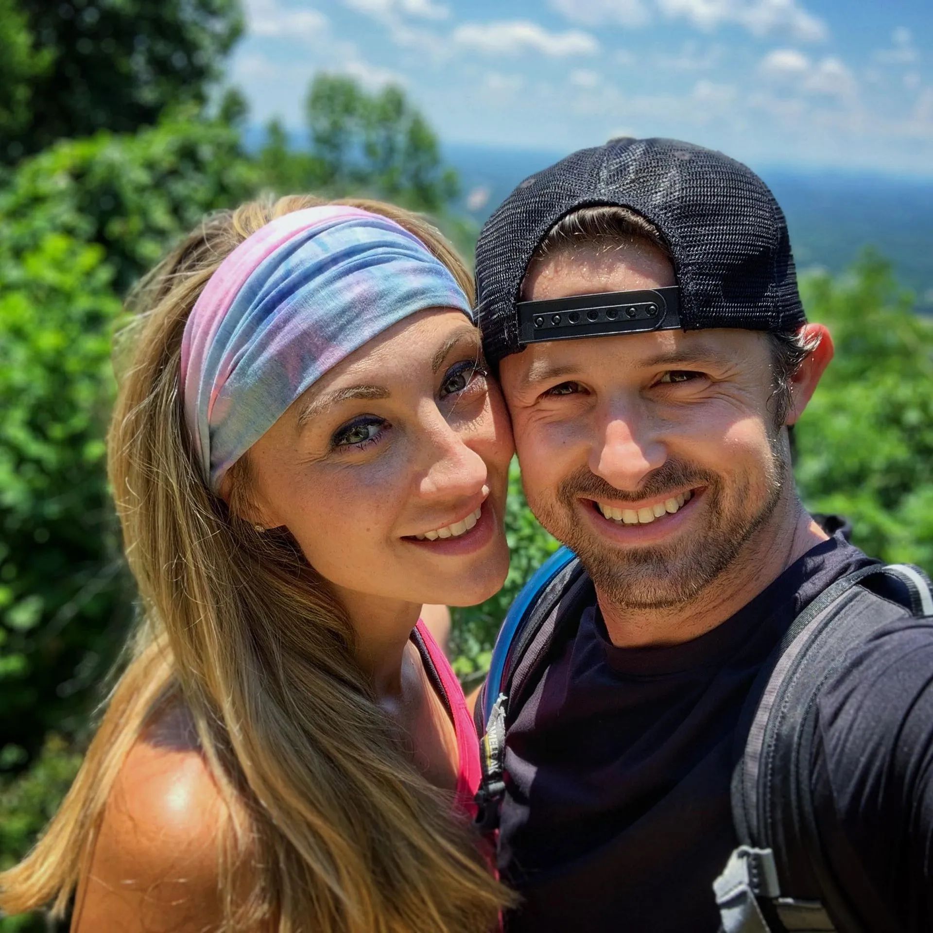A man and a woman are posing for a picture together . the woman is wearing a headband.