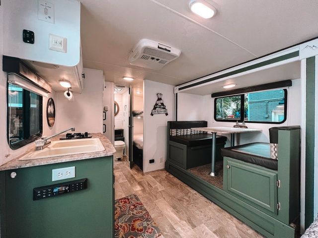 The inside of a rv with a kitchen , dining area , and a couch.