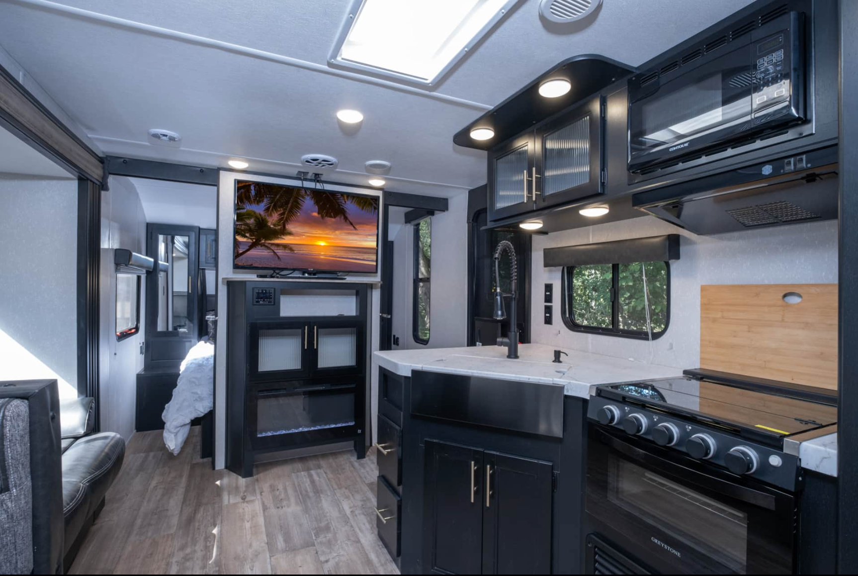 A kitchen in a rv with a flat screen tv on the wall.