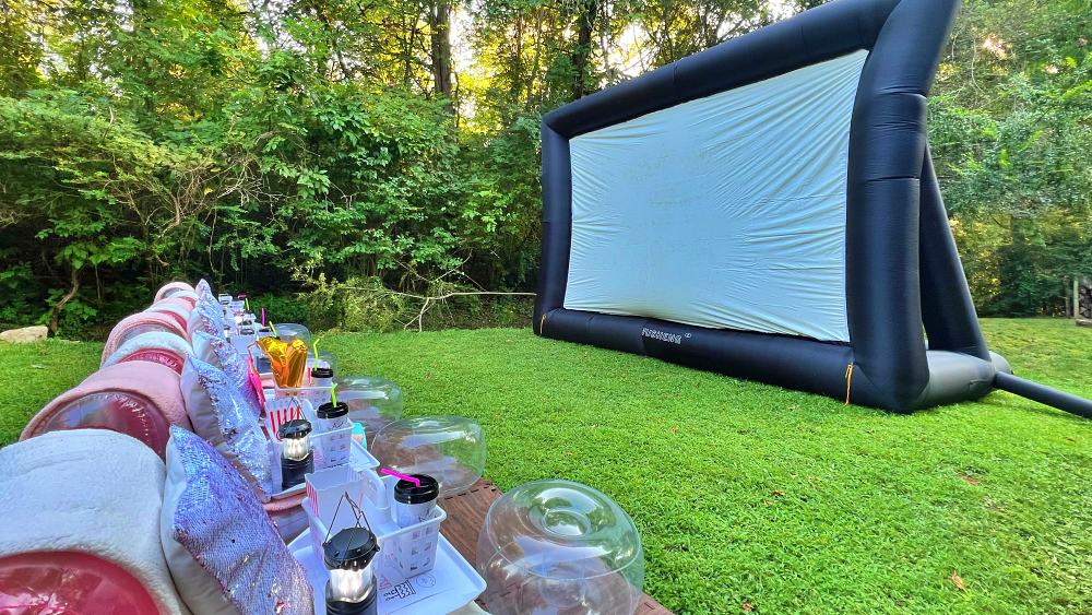 A large inflatable screen is sitting on top of a lush green field.