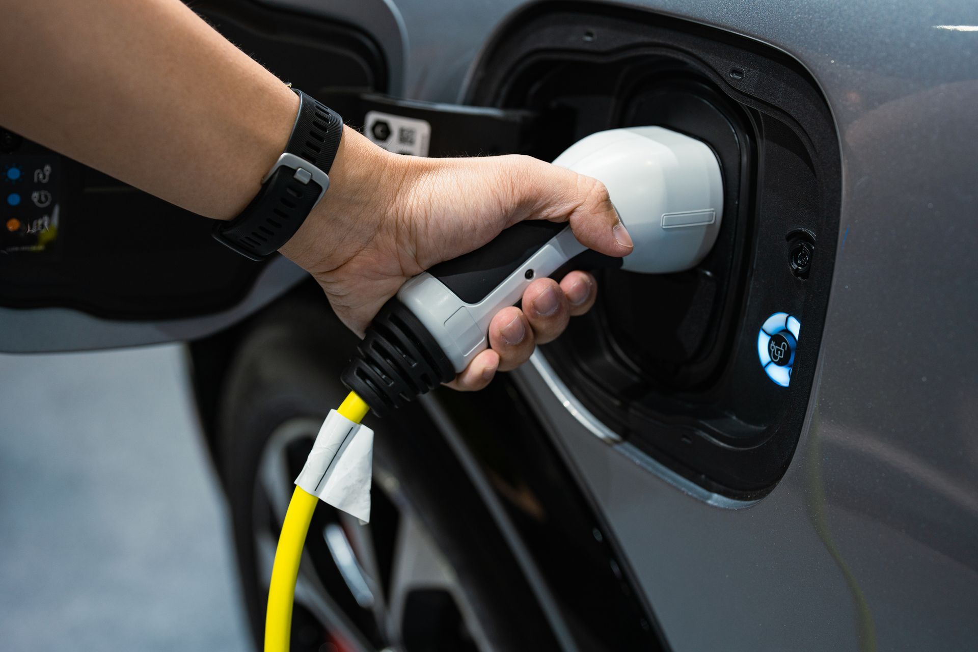 Hand plugging in an electric vehicle charger in Olympia, WA, highlighting convenient and eco-friendl