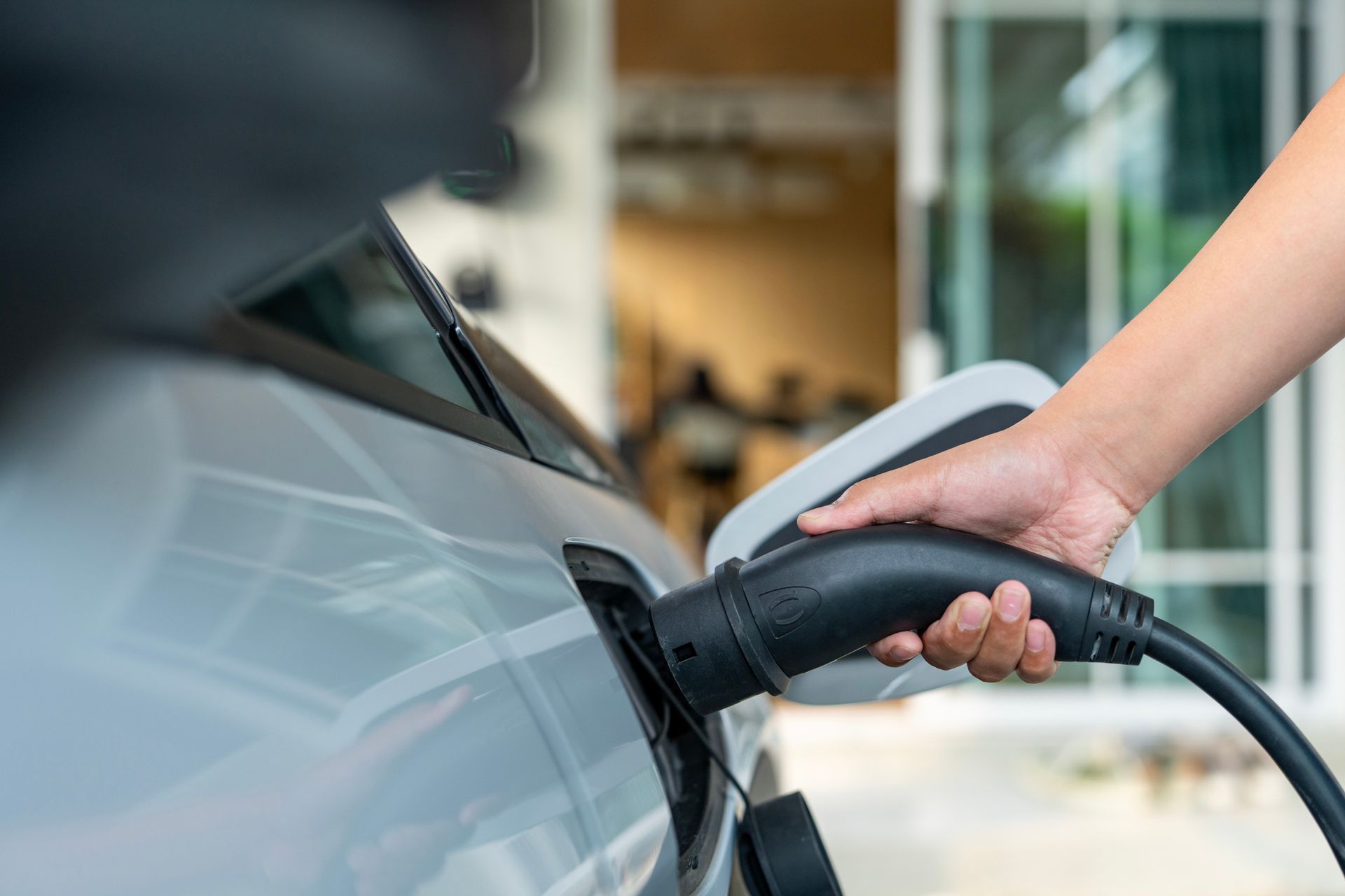 Close-up of an electric car being plugged into a charger at a home charging station. Close-up of an electric car being plugged into a charger at a home charging station.