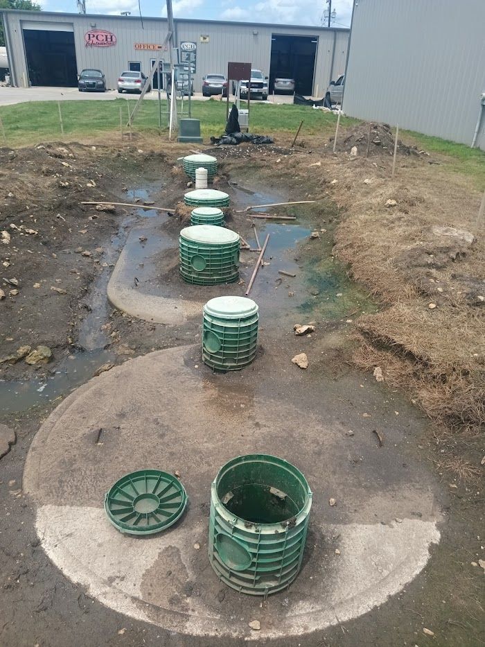 A group of green buckets are sitting in the dirt in front of a building.