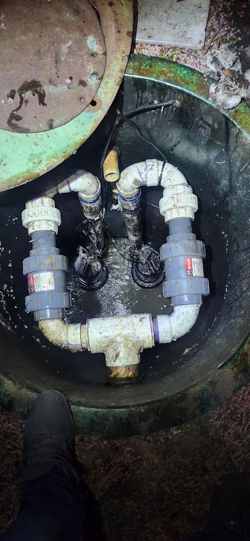 A bunch of pipes are sitting in a hole in the ground.