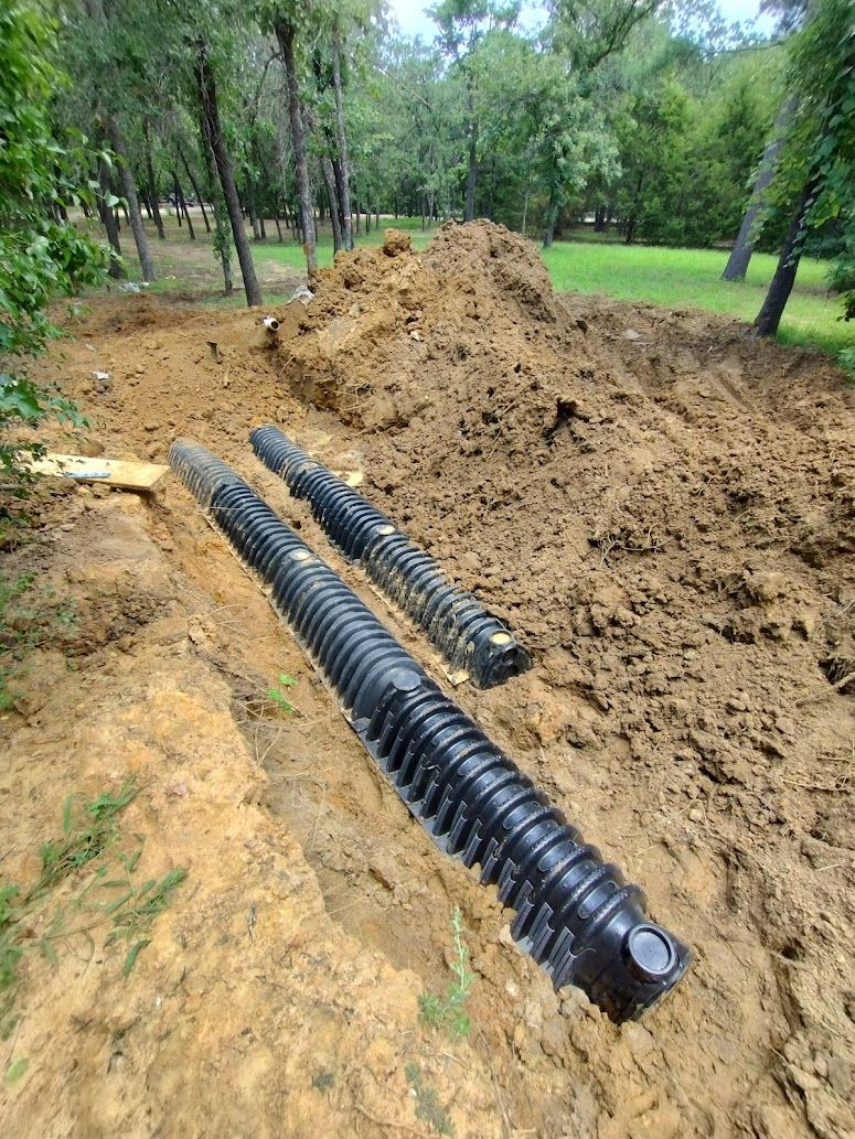 A couple of black pipes are sitting in the dirt.