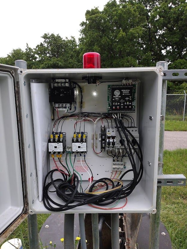 A box with a lot of wires and a red light on top of it.