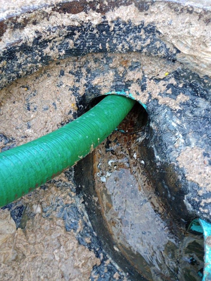 A green hose is coming out of a hole in the ground.