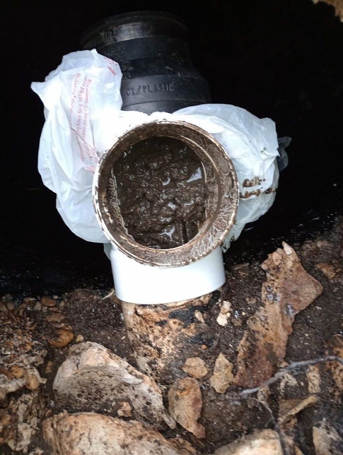 A dirty pipe is sitting on top of a pile of rocks.