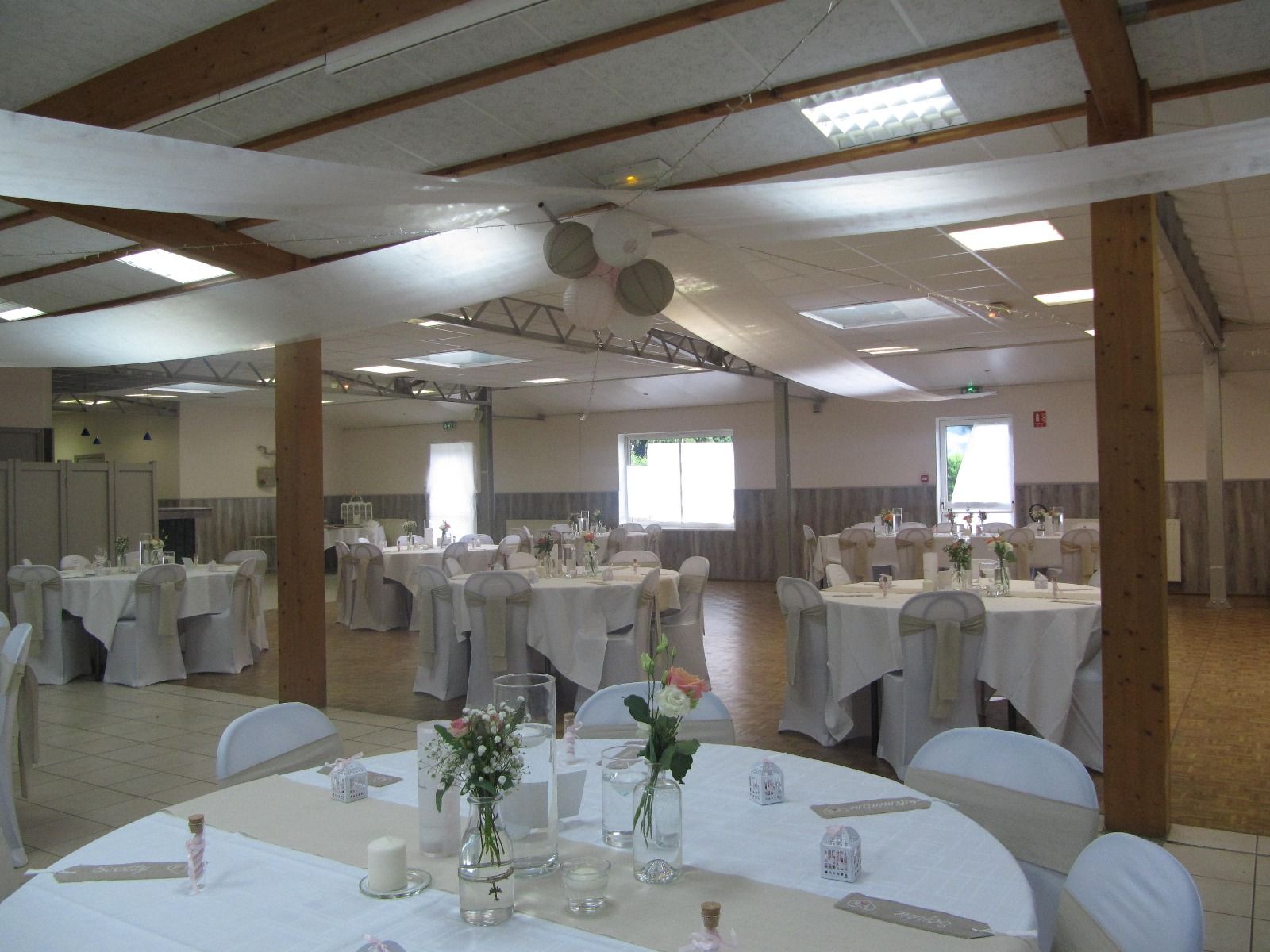 Une grande salle avec tables et chaises installées pour une réception de mariage.