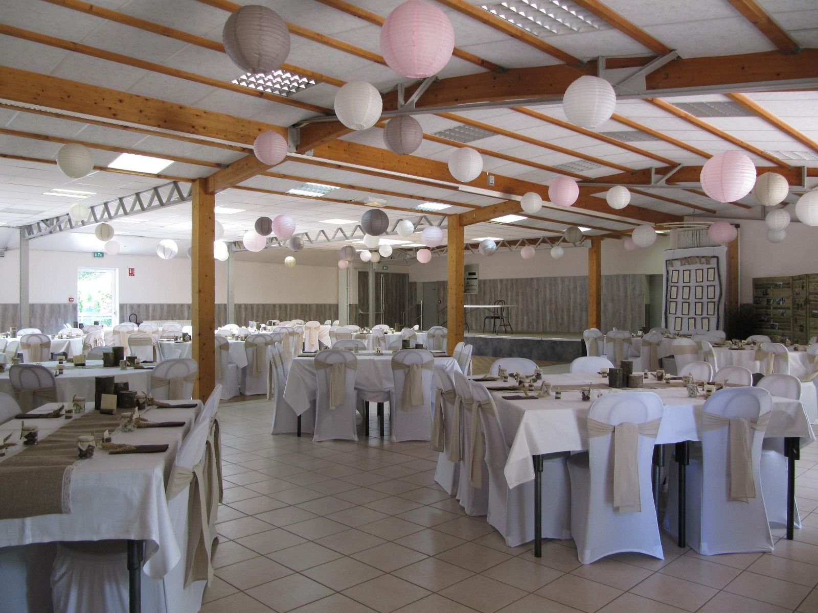 Une grande salle avec tables et chaises installées pour une réception de mariage.