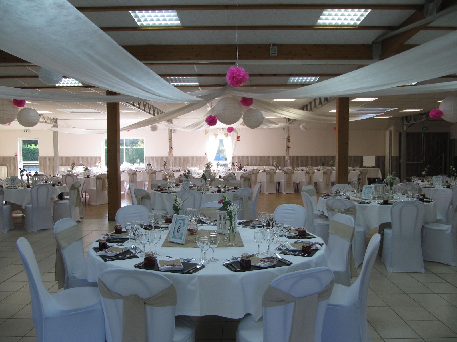 Une grande salle avec des tables et des chaises installées pour une réception de mariage