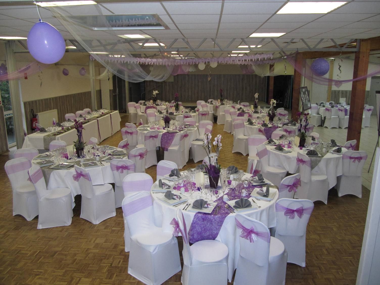 Une grande pièce avec des tables et des chaises violettes et blanches