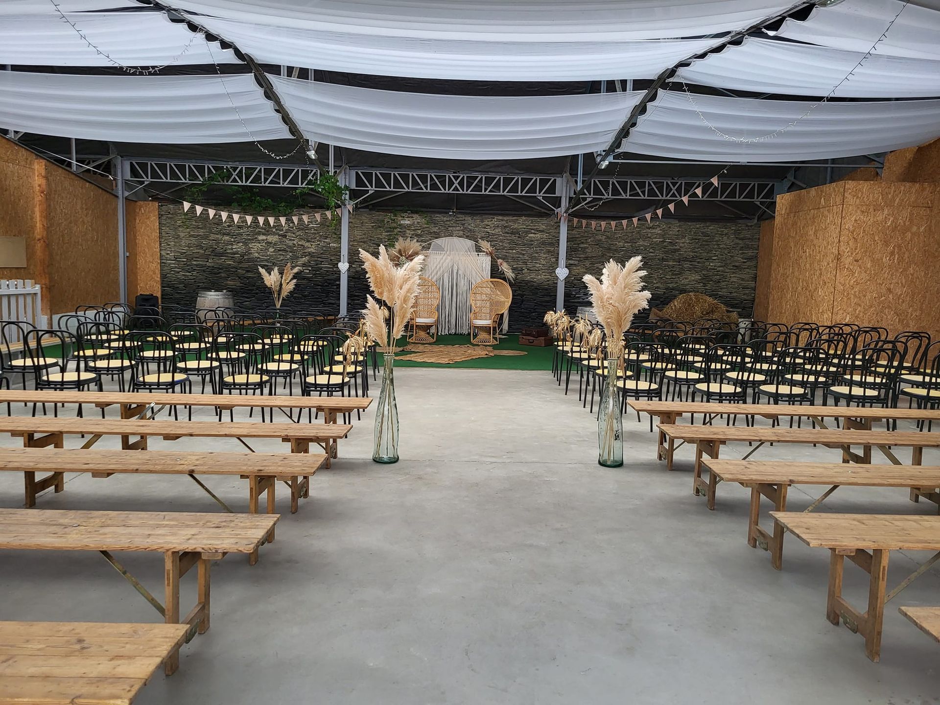 Une grande salle remplie de bancs et de chaises en bois pour une cérémonie de mariage.