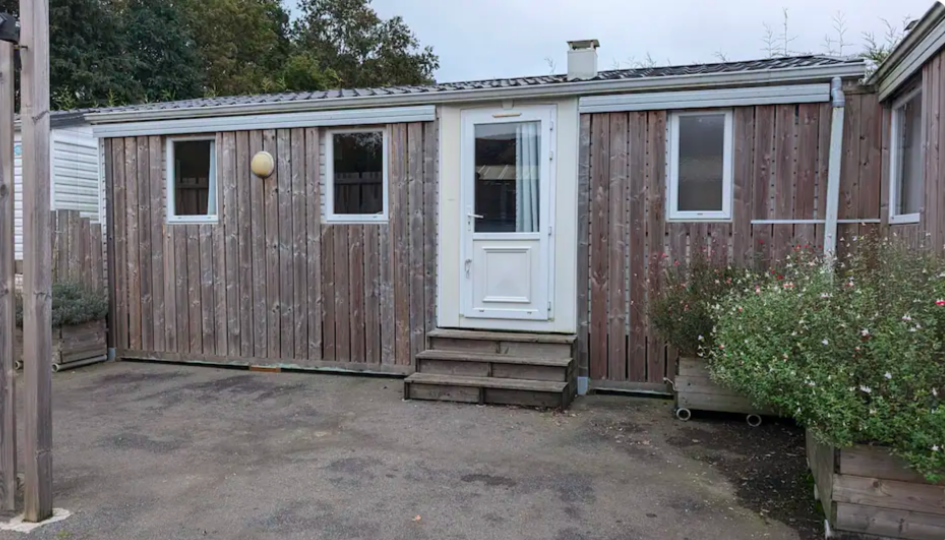 Une petite maison en bois avec une porte blanche et des escaliers.