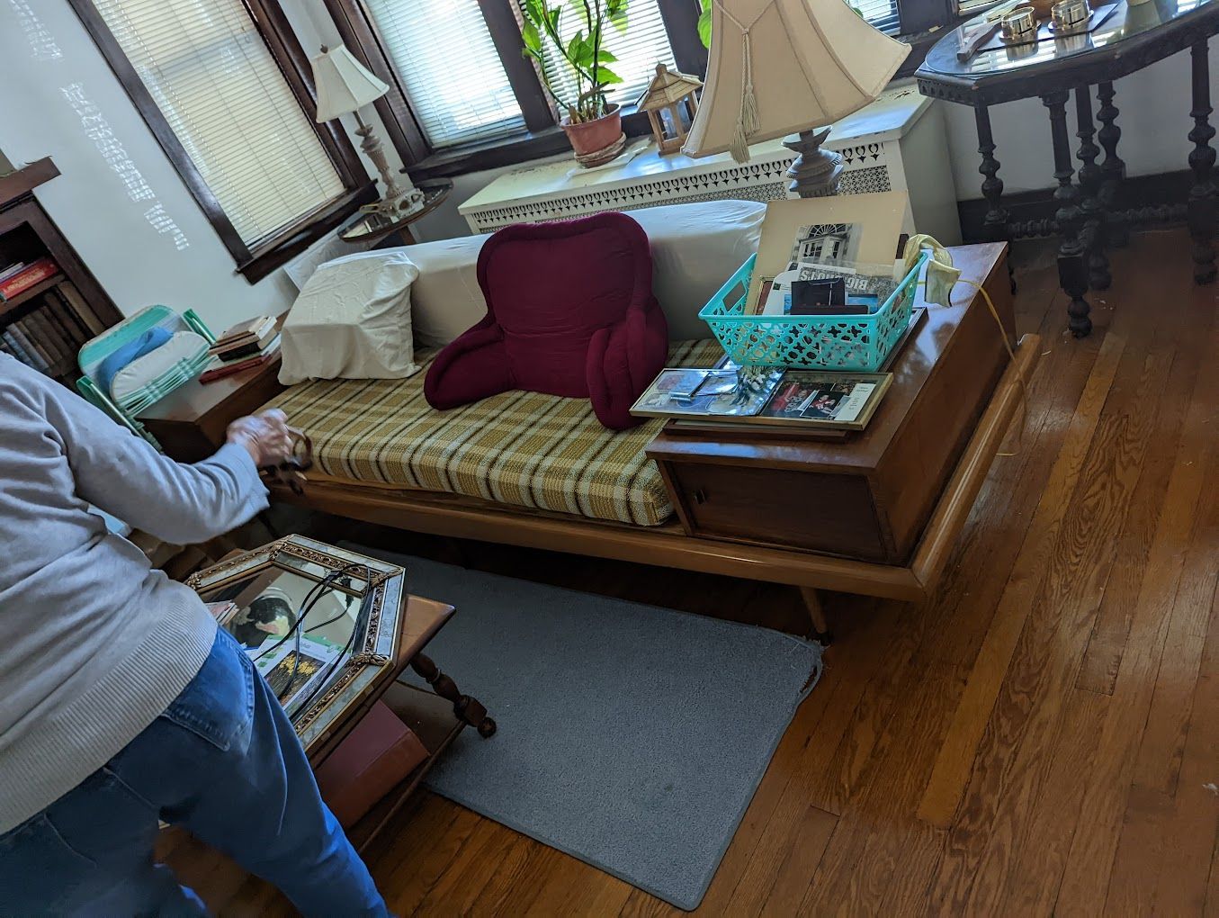 A woman is standing in a living room next to a couch.
