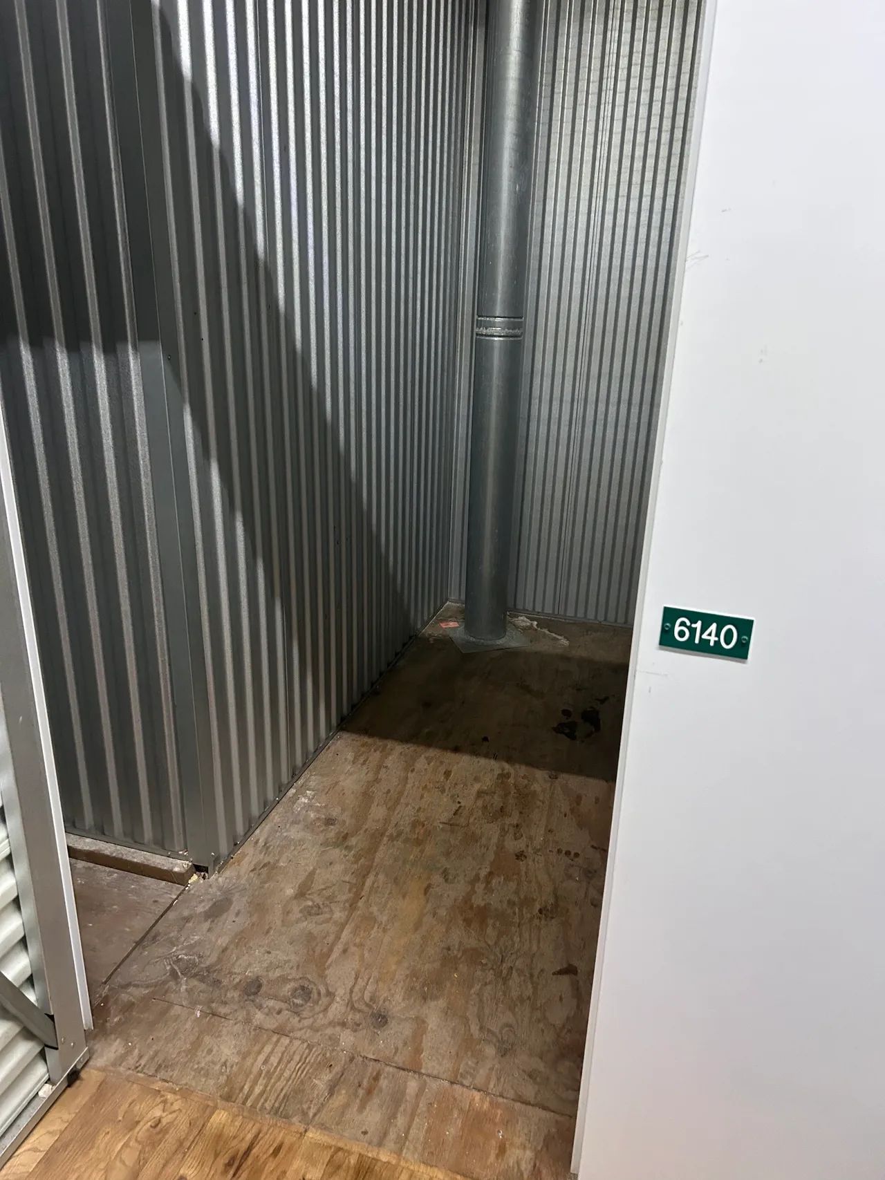 A small room with a metal wall and a wooden floor.