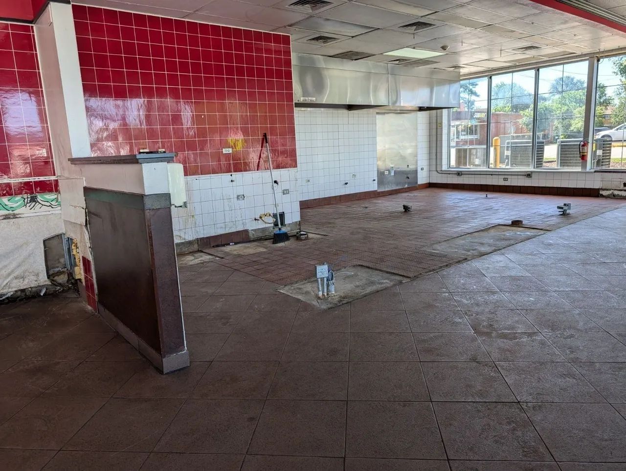 A large empty room with red tiles on the walls and floor.