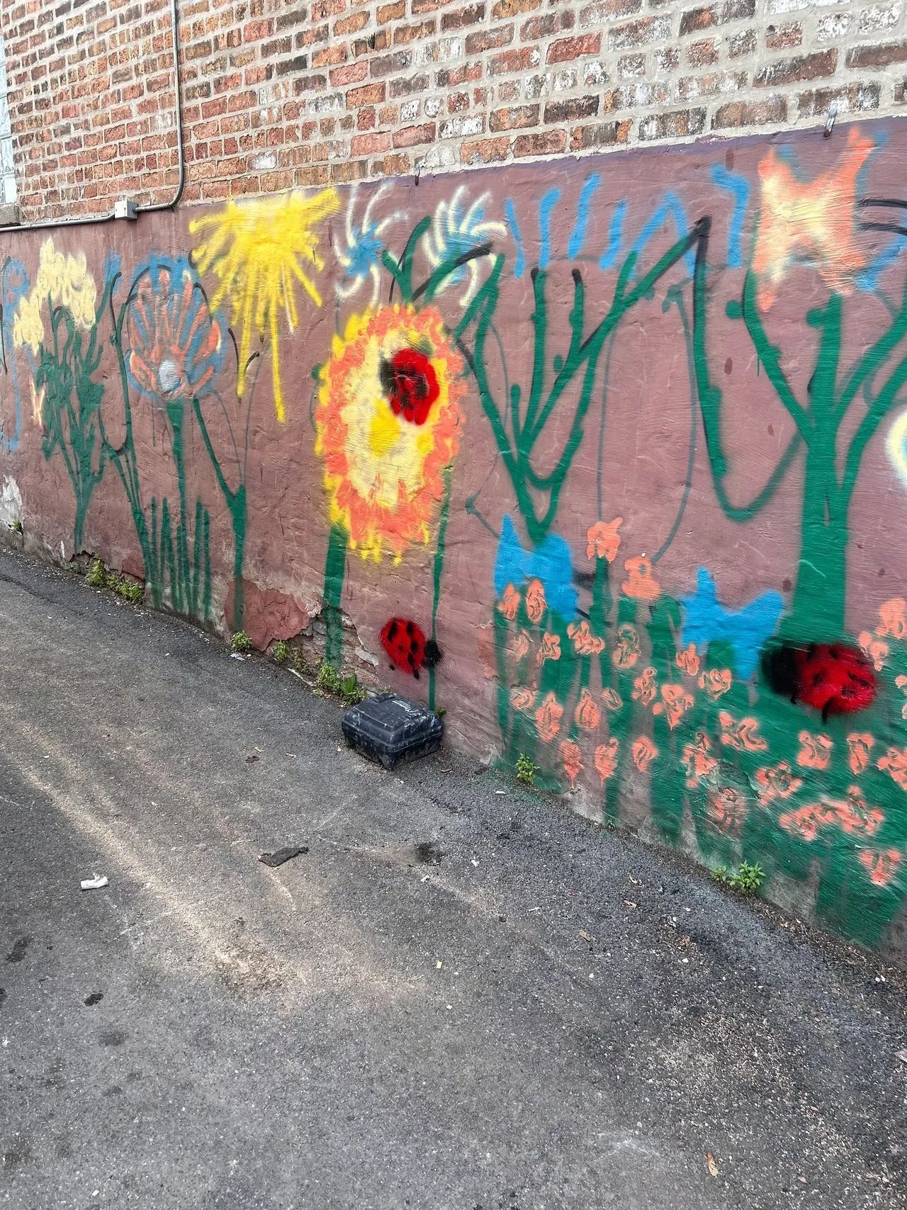 A brick wall with graffiti on it and flowers painted on it.