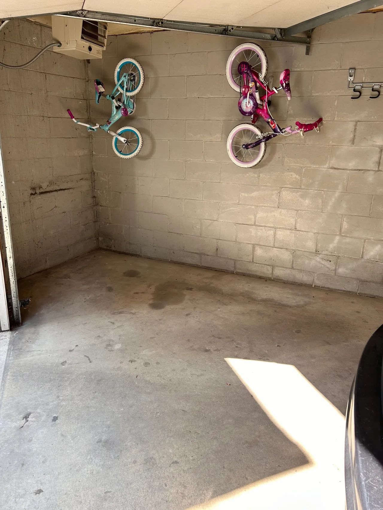 Two bicycles are hanging on a brick wall in a garage.