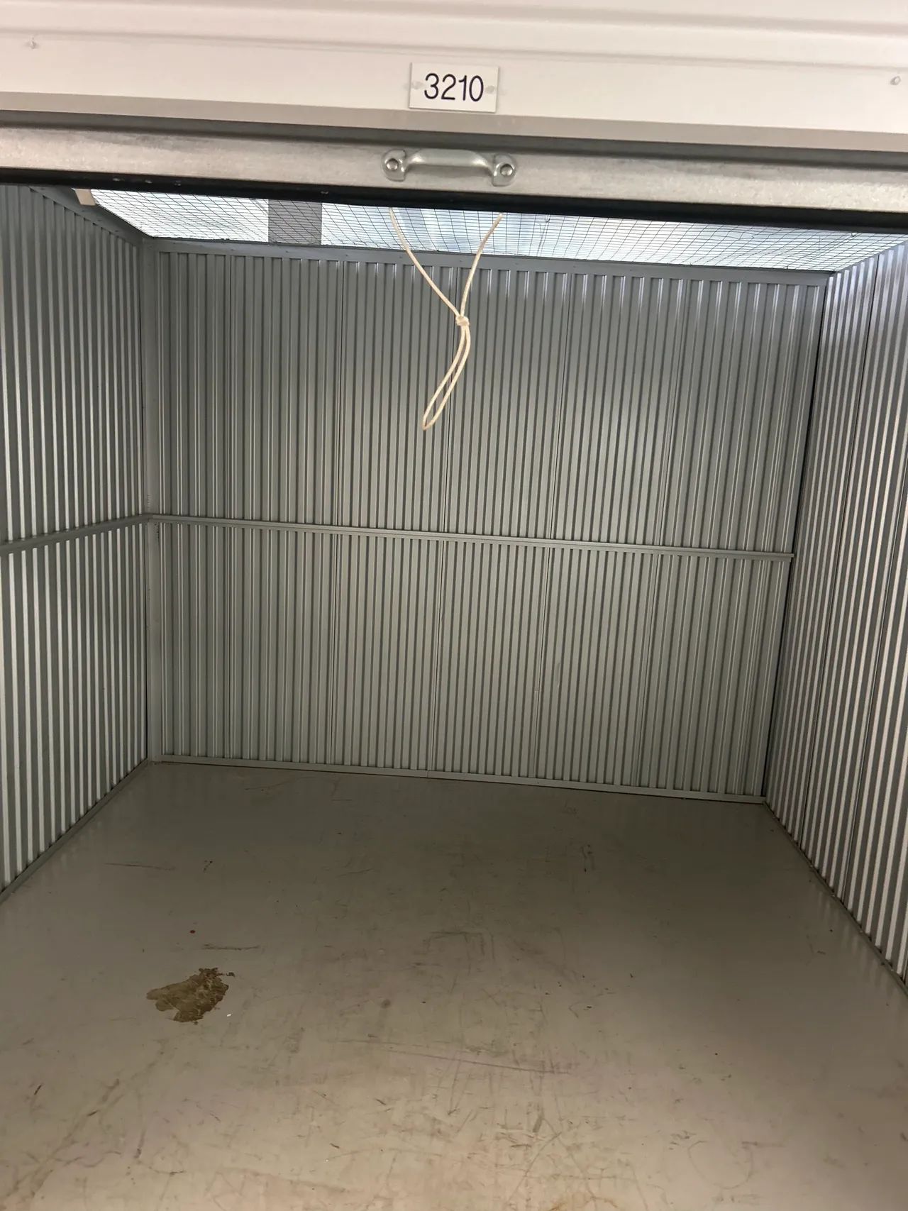 An empty storage unit with a telephone hanging from the ceiling.