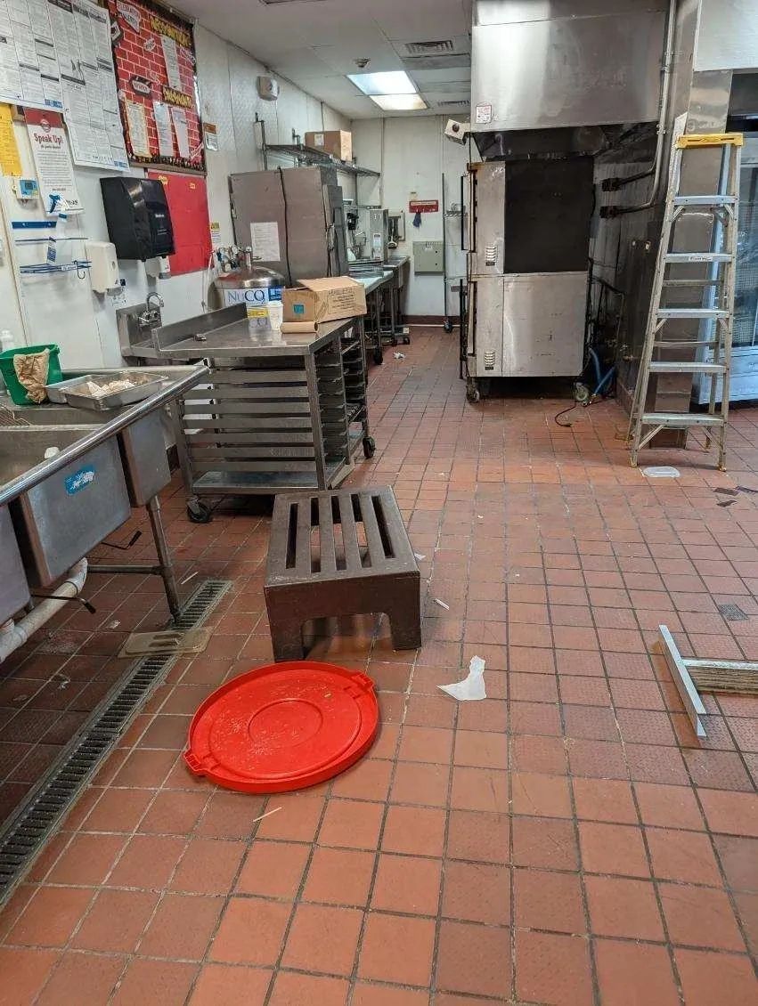 A kitchen with a red lid on the floor and a ladder.
