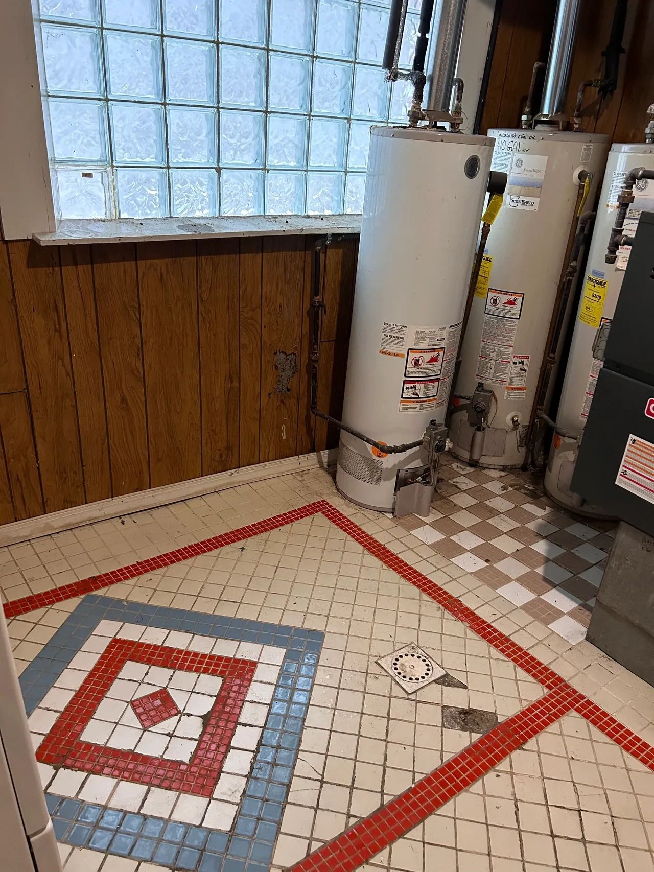 A room with two water heaters and a mosaic floor.