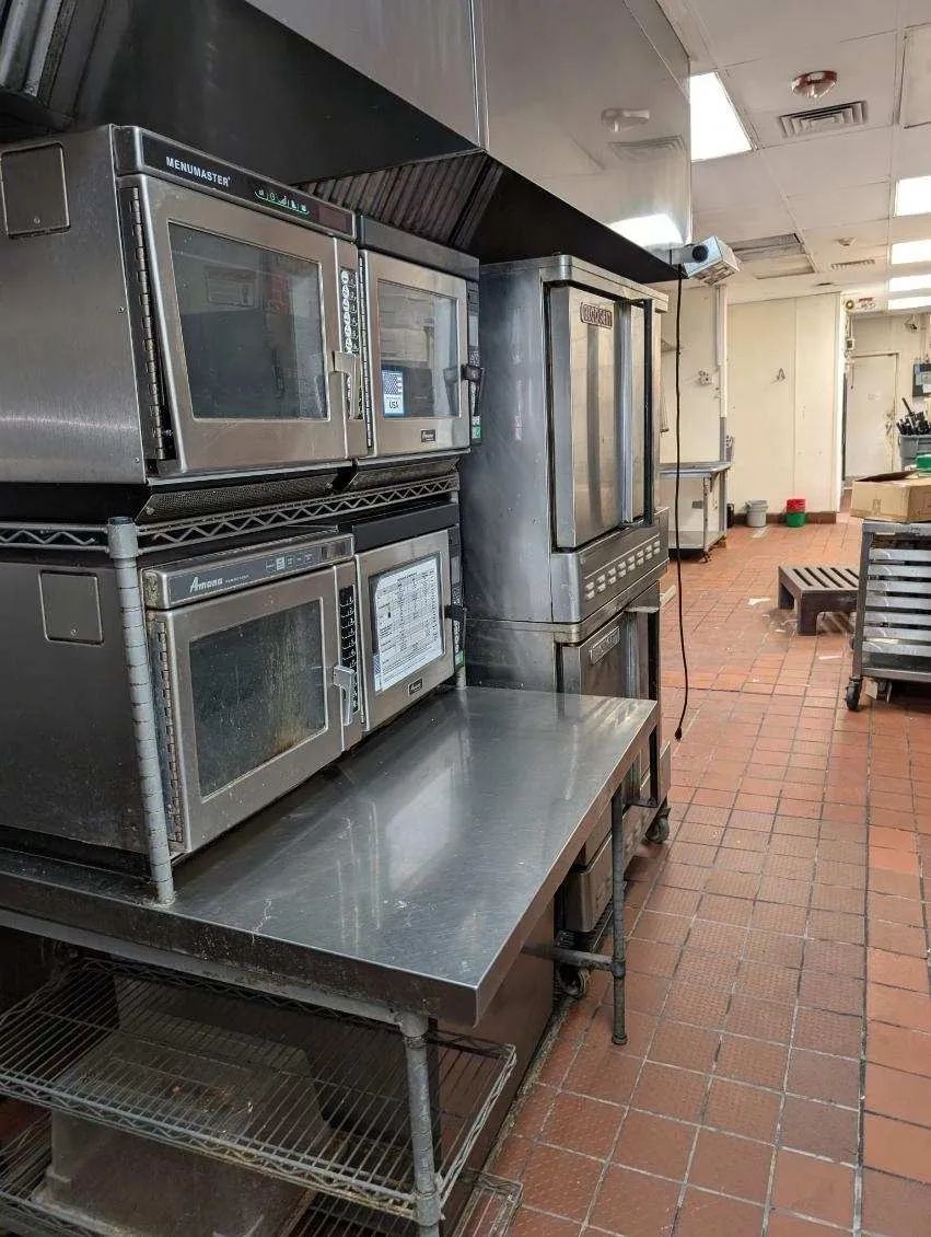 A kitchen with a lot of stainless steel appliances stacked on top of each other.
