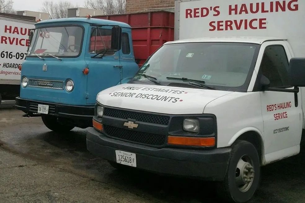 Two red 's hauling service trucks are parked next to each other