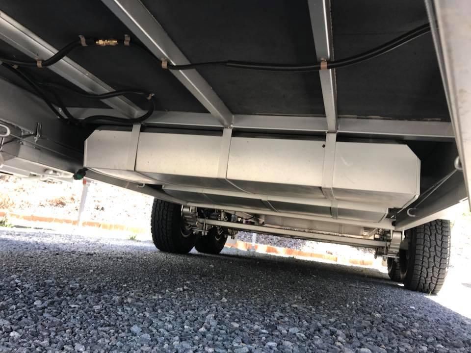 A Trailer With a Large Tank Underneath It is Parked on Gravel — J & D Caravans In Tamaree, QLD