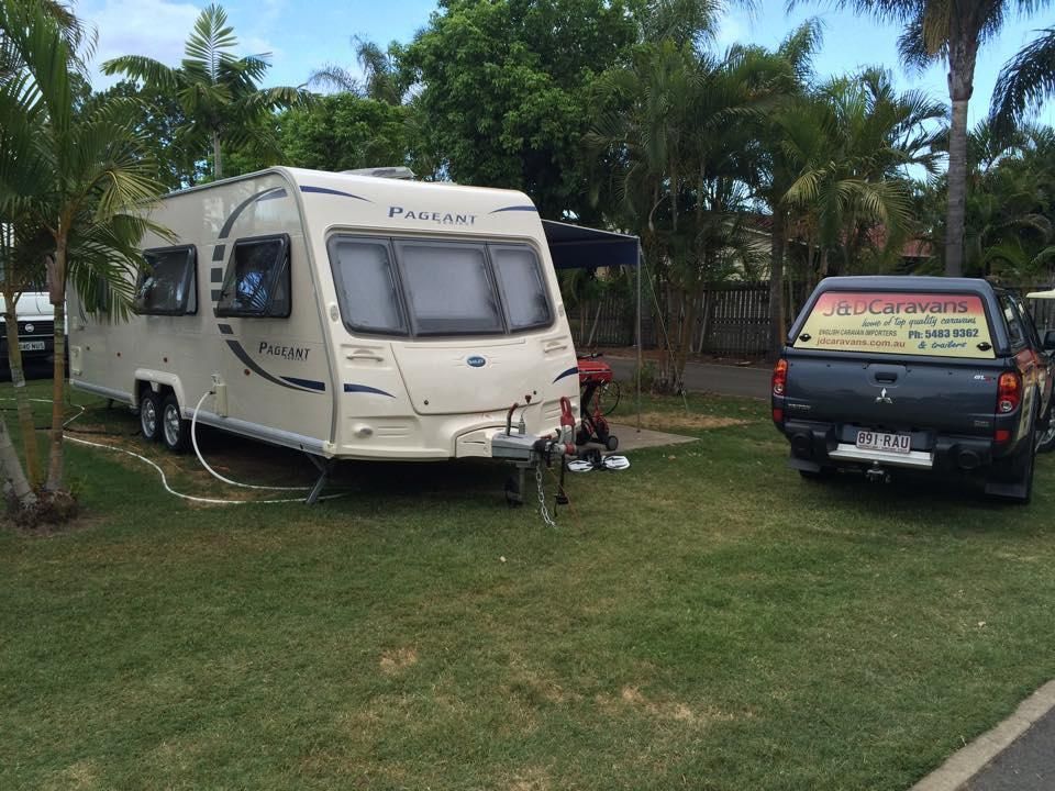 A Caravan is Parked Next to a Truck in a Grassy Area — J & D Caravans In Cooroy, QLD
