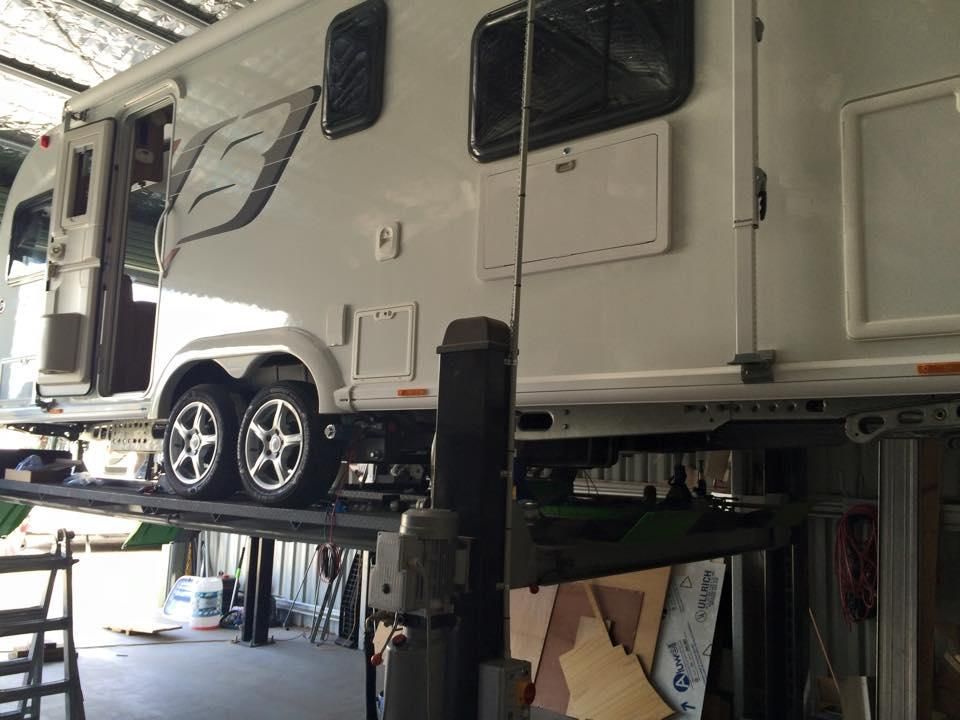 A White Rv is on a Lift in a Garage — J & D Caravans In Cooroy, QLD