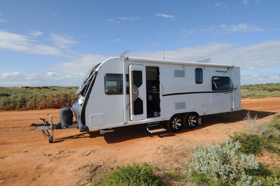 A White Caravan is Parked on the Side of a Dirt Road — J & D Caravans In Tin Can Bay, QLD