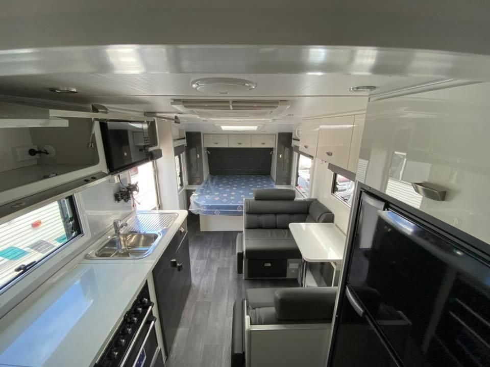 The Inside of a Rv With a Bed , Couch , Table and Sink — J & D Caravans In Tamaree, QLD