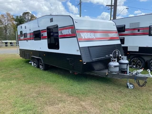 A Dump Trailer is Parked in a Parking Lot Next to a Building — J & D Caravans In Glenwood, QLD