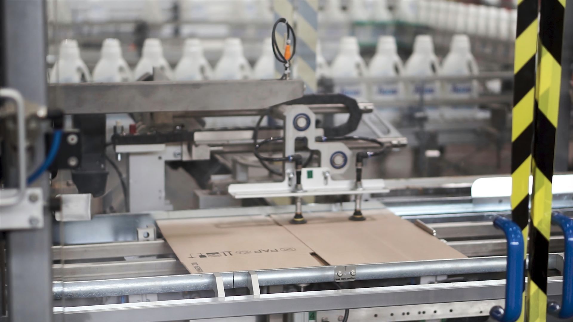 A robotic arm placing a cardboard box on a conveyor belt in a factory.